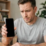 Homme tenant un Samsung Galaxy avec écran noir dans un bureau à domicile, cherchant à résoudre le problème